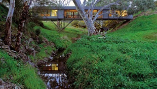 The house touches its unique site lightly, with just four concrete pads supporting the delicate steel frame.